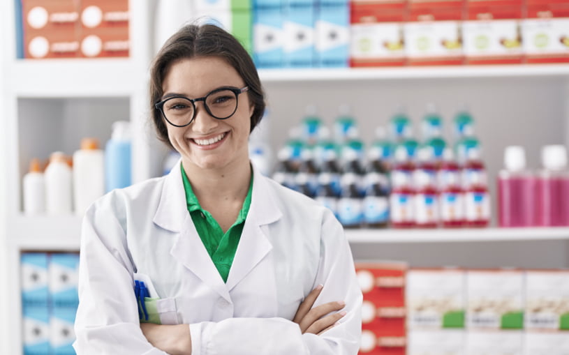 farmaceutica-joven-hispana-sonriendo-segura-de-pie-con-gesto-de-brazos-cruzados-en-la-farmacia Atención farmacéutica